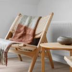 Wooden chair with woven seat and blanket, beside round table with bowl.
