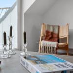Table with puzzle, mugs, and candle holders near window with balcony view.