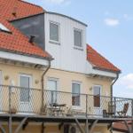 Apartment with balcony, red roof, and white windows under blue sky.