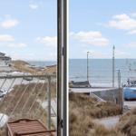 View from balcony over harbor with fishing boat and beach.