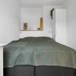 Bedroom with bed, wardrobe, and wall shelf with decorative items.