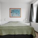 Bedroom with bed, wall art, and window with curtains.