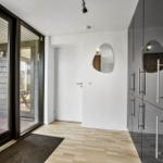 Entrance with glass doors, wooden floor, and modern mirror on the wall.