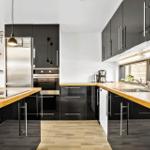 Modern kitchen with dark cabinets, wooden countertops, and stainless steel appliances.