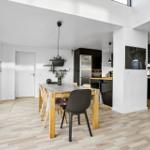 Dining room with table, chairs, and kitchen area in background.