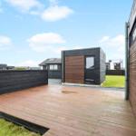 Deck with wooden floor and fence. Background: modern houses and green area.