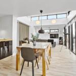 Dining area with table and chairs, living area with sofa and TV, large windows and telescope.