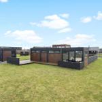 Modern wooden cabin with large garden and terrace under blue sky.