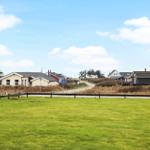Lush green fields with view of vacation homes and a path