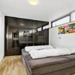 Bedroom with bed, wardrobe, and windows.