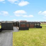 Modern villa with wooden facade and large garden under blue sky.