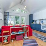 Ein Raum mit rotem Sofa, blauer Küche und Holzboden.