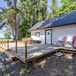 Wohnhaus mit Holzterrasse, Sonnenliegen und Blick auf den See.