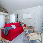 Ein Wohnzimmer mit rotem Sofa, Holzstuhl und Segelwandtapete.