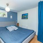 Schlafzimmer mit blauer Wand, Bett und TV. Holzfußboden und blaue Vorhänge.