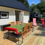 Terrasse mit Tisch, Stühlen und Liegestühlen vor einem Haus.
