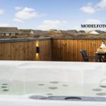Whirlpool auf Terrasse mit Holzgeländer und Sitzgruppe im Hintergrund.