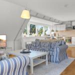 Wohn- und Küchenbereich mit Sofa, TV und Fensterblick.