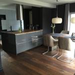 Küche mit Essbereich, Holzboden und modernen Lampen.