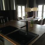 Küche mit Holzinsel, Spüle und Kochfeld. Essbereich mit Tisch und Stühlen.