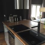 Küche mit Holzplatte, Kochfeld und Spüle. Hintergrund zeigt Essbereich.