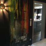 Schlafzimmer mit großer Wandmalerei und Sicht in die Küche.