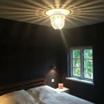 Schlafzimmer mit Bett, Fenster und Kristalldeckenleuchte.