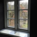 Fenster mit Blick auf einen Garten und eine Hütte mit rotem Dach.