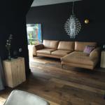 Ein Wohnzimmer mit braunem Sofa, dunklen Wänden und Holzboden.