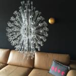 Ein Sofa mit Kissen und einer Glasleuchte an der Wand.