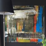 Großes abstraktes Gemälde an dunkler Wand neben Stehlampe und Pflanze.