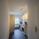 Küche mit Waschmaschine, Kochfeld und Fenster zur Außenseite