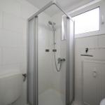 Duschkabine mit Duschbrause, Toilette und Fenster