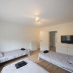 Drei Betten, Fernseher und Schränke im Schlafzimmer