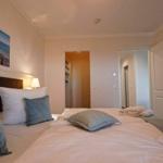 Schlafzimmer mit Bett, Kissen und Wandbild. Tür führt in angrenzenden Raum.