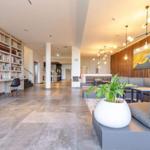 Großer Empfangsbereich mit Bücherregalen, Sitzgelegenheiten und einer Pflanze.