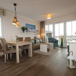 Wohn- und Essbereich mit Tisch, Stühlen, Sofa und Blick auf Balkon.