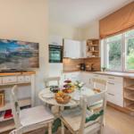 Küche mit Esstisch, Fernseher und Fenster mit Blick auf Grün