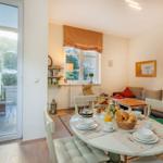 Esszimmer mit Tisch, Stühlen und Frühstück. Wohnbereich mit Sofa und Fenster.