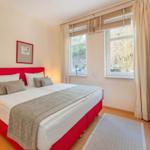 Schlafzimmer mit rotem Bett, Fenster und Kleiderschrank.