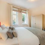 Schlafzimmer mit Bett, Kleiderschrank und Fenster mit Blick auf Grün.