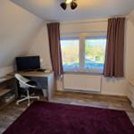 Schlafzimmer mit Bett, Schreibtisch, Fenster und Teppich.