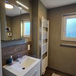 Badezimmer mit Waschbecken, Spiegel und Fenster.