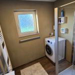 Badezimmer mit Dusche, Waschmaschine und Heizkörper.