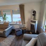 Wohnzimmer mit Sofa, Kamin und Fenstern.