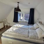 Schlafzimmer mit Doppelbett, Schrank und Fenster mit Vorhängen.