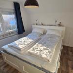 Schlafzimmer mit Doppelbett, Fenster und Holzboden.