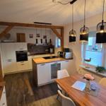 Küche mit Essbereich, Holzboden und modernen Hängelampen.