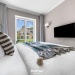 Schlafzimmer mit Bett, TV und Fenster zum Balkon.