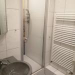 Badezimmer mit Dusche, Waschbecken und Heizkörper
